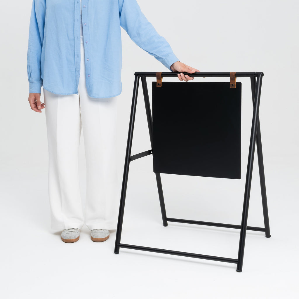 Zwart metalen stoepbord A-frame naast een persoon, formaat ter indicatie