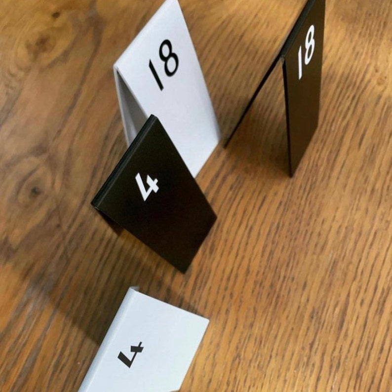 Zwarte en witte aluminium tafelnummers op een houten tafel