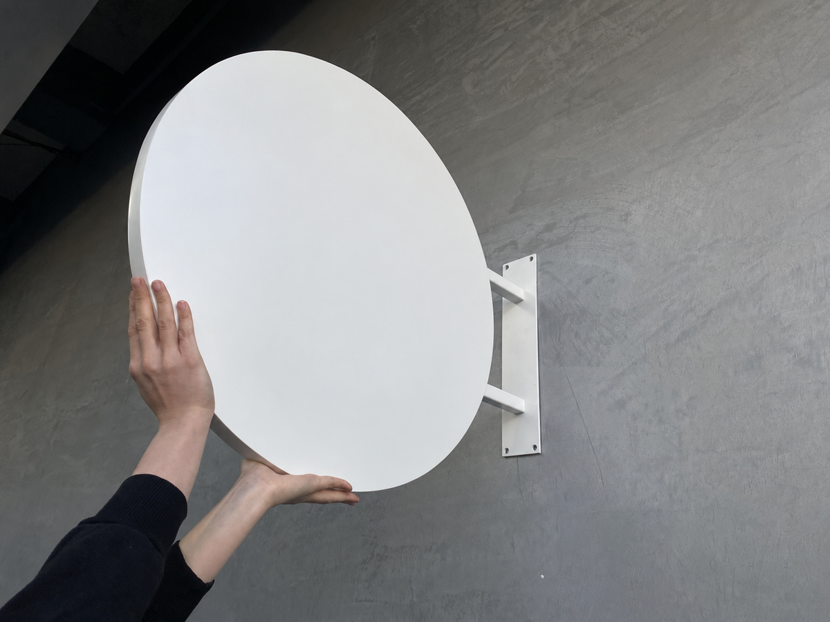 Rond wit uithangbord van aluminium, dubbelzijdig, aan de gevel